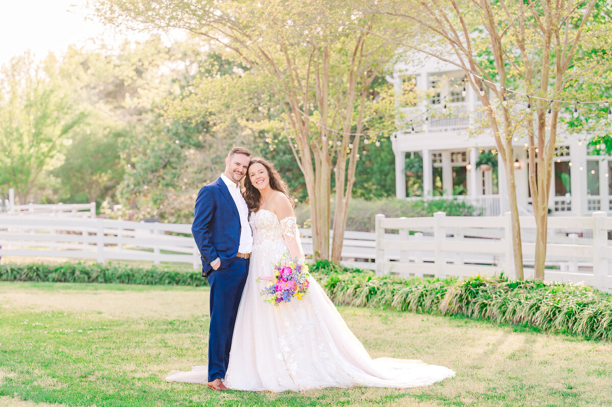 A groom in a blue tux and a sweet brunette bride holding a colorful wedding bouquet during the fall time at their destination wedding in Wilmington by JoLynn Photography