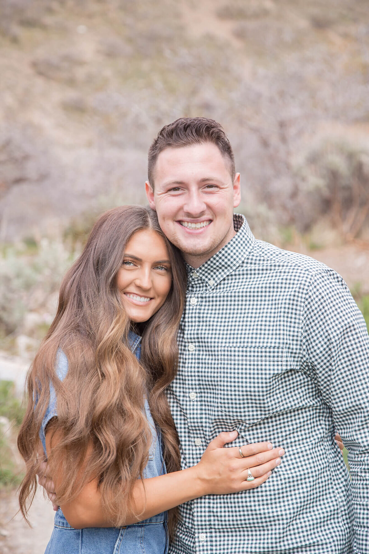 Beautiful brown haired woman in denim hugging smiling man in a green checkered shirt