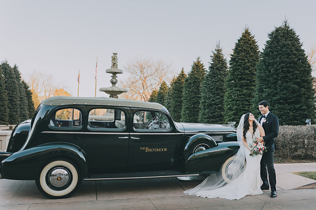 Wedding couple poses in front of the hotel car at The Broadmoor in Colorado Springs.