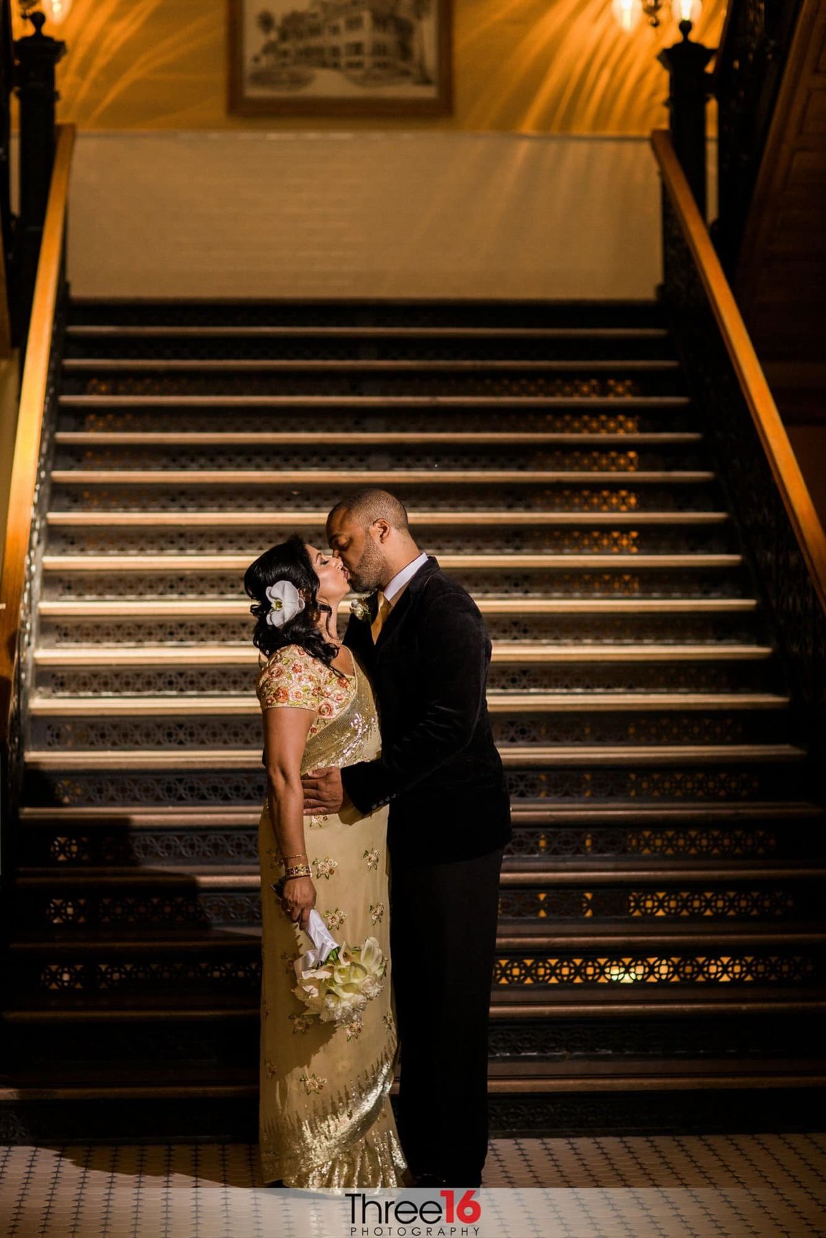 Bride and Groom stop at the bottom of the stairs for a kiss