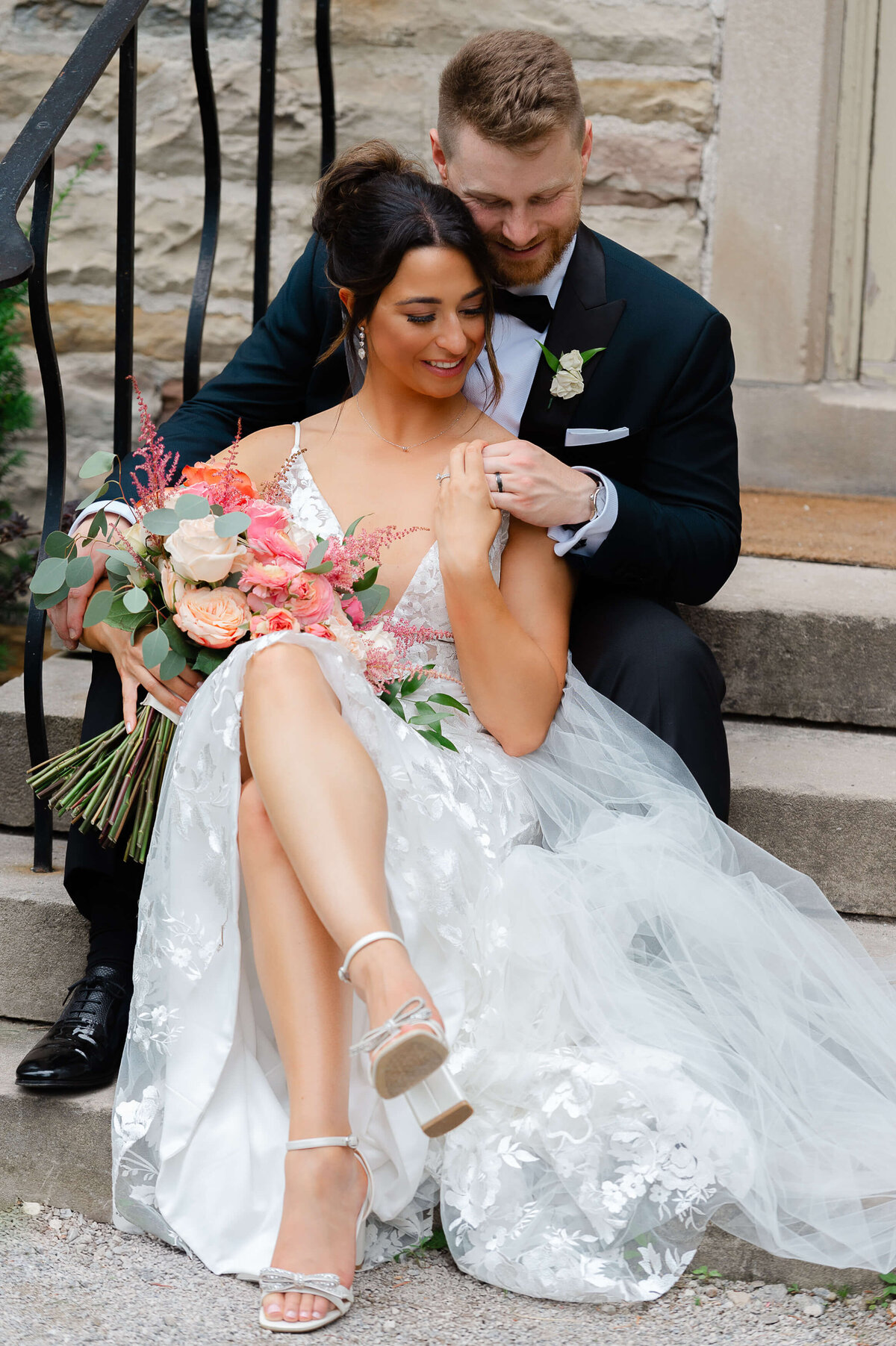 a bride and groom sitting on steps outside Eaton Hall looking at their rings.  Captured by Ottawa wedding photographer JEMMAN Photography