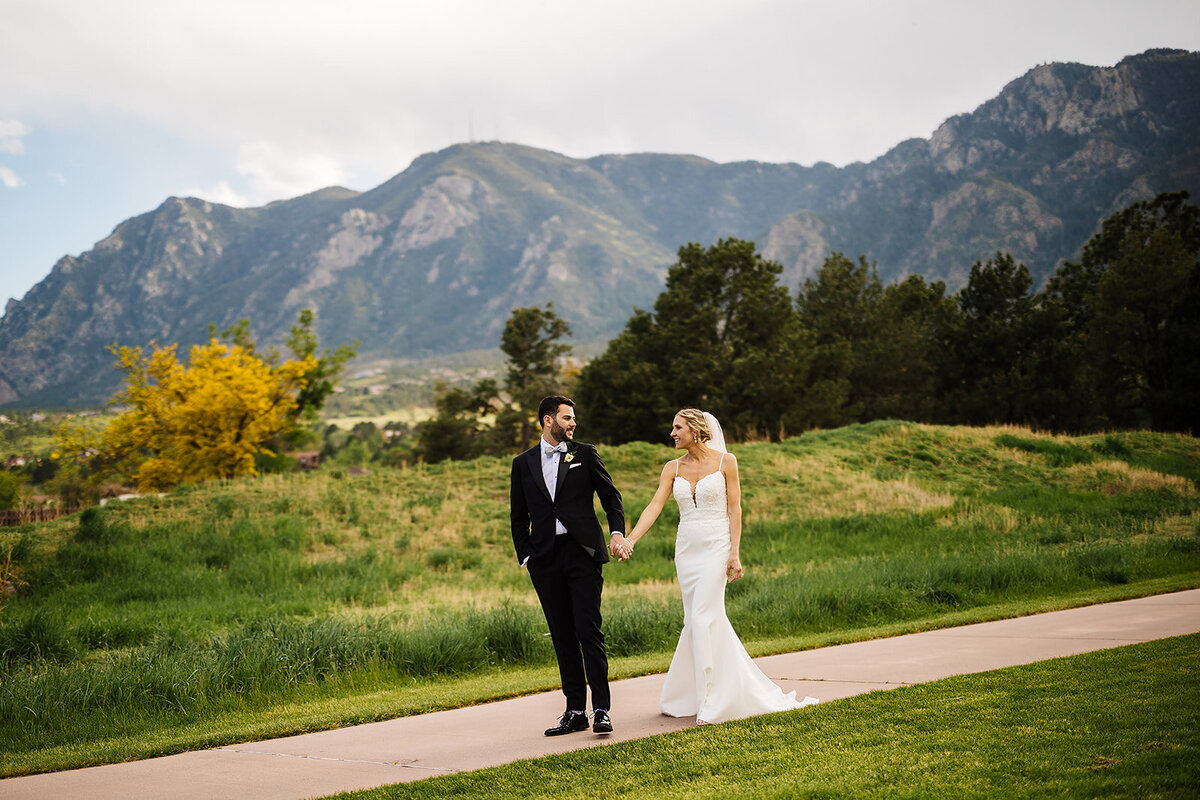 Bride and groom walk on their wedding day with a beautiful view at Cheyenne Mountain Resort.