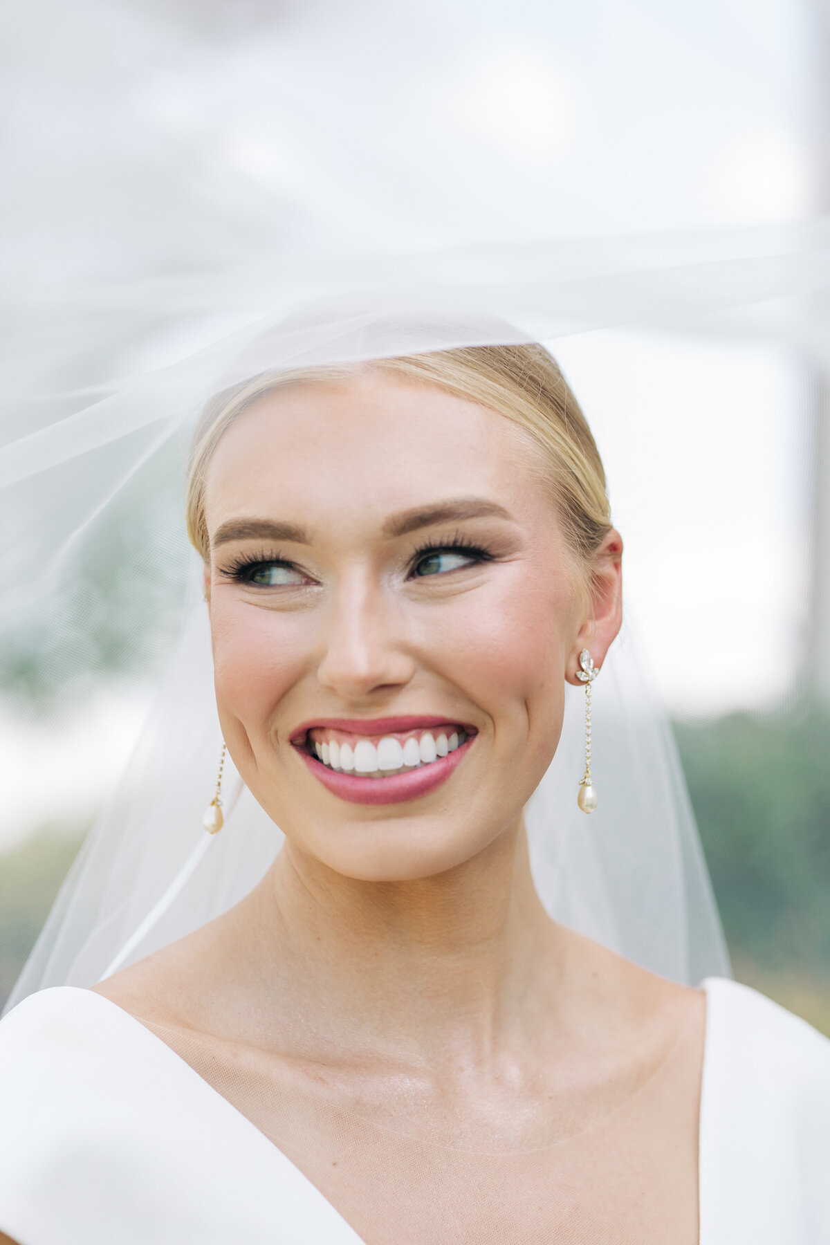 Bride smiling underneath wedding veil