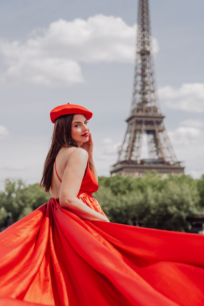 Classic Paris portrait with woman in long red dress and matching beret against Eiffel Tower view