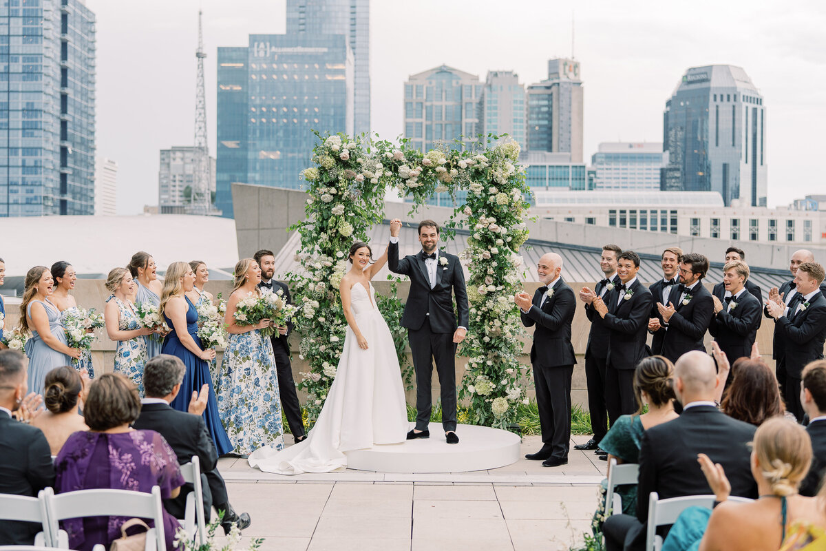 Oversized ceremony floral arch for summer wedding. Classic and timeless floral design in white, cream, taupe, champagne, and green. Lush ceremony florals for garden-inspired summer wedding. Florals composed of roses, hydrangea, baby’s breath, and organic greenery. Design by Rosemary & Finch Floral Design.