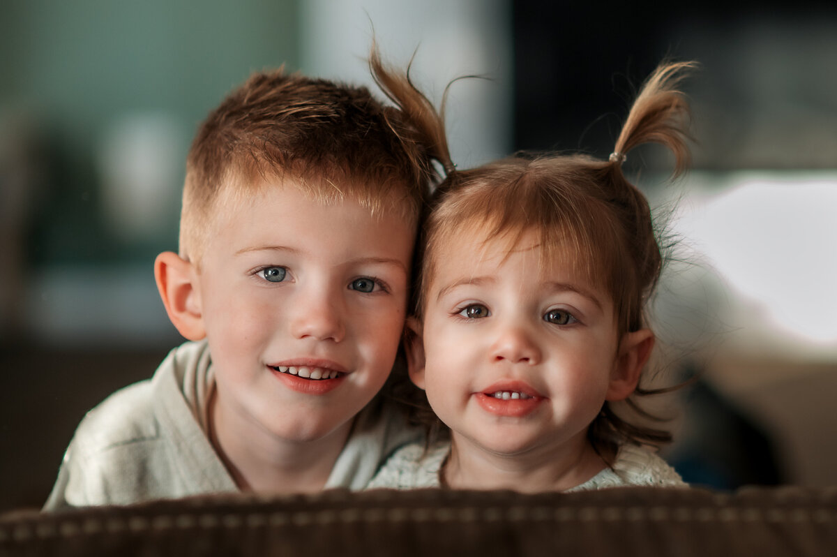 Brother and sister smiling together during a relaxed indoor photo session.