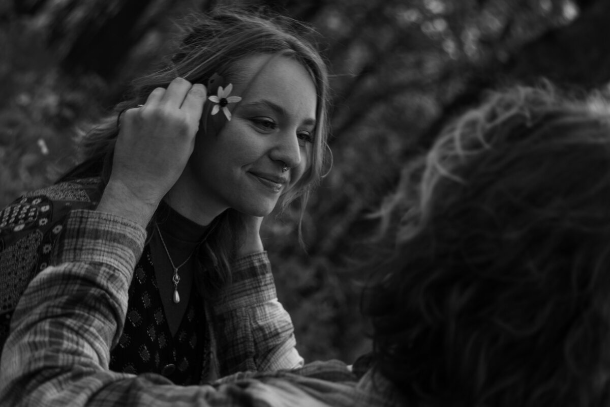 Guy putting a flower in his girlfriends hair in black and white 