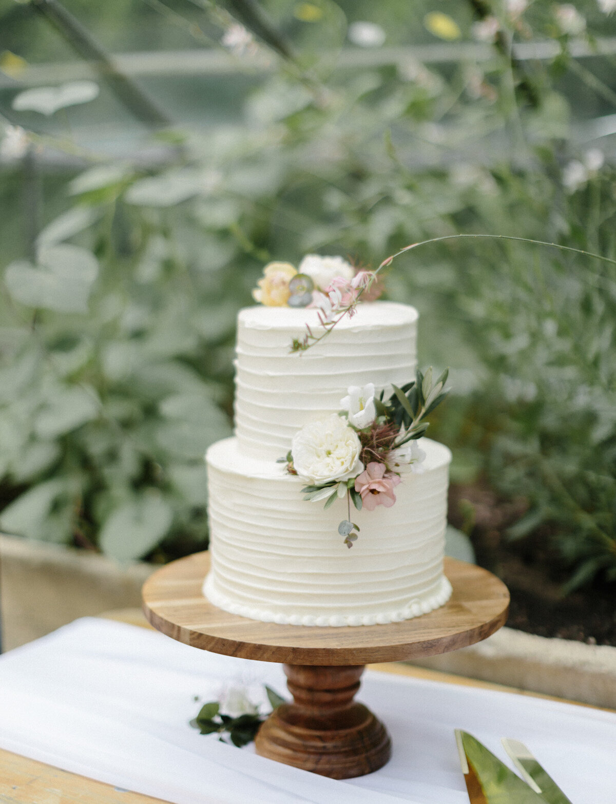simple frosting wedding cake with flowers, greenhouse wedding in Michigan