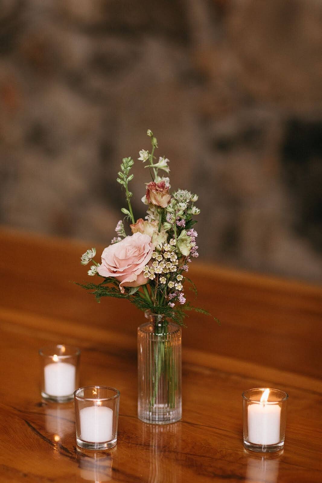 Small bud vase floral arrangement sits atop a wedding reception table at Maysara Winery.