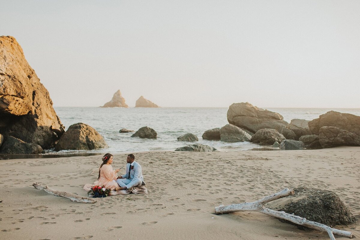 Couple reading letters on an Oregon Coast beach on their elopement day