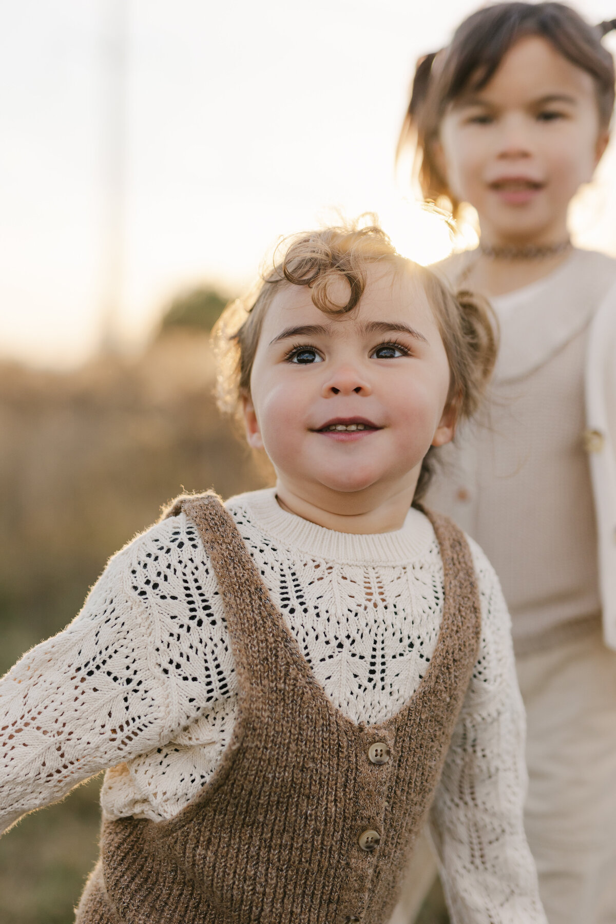 A little girl is looking up in the sky while her older sister is behind her in a Toronto family session