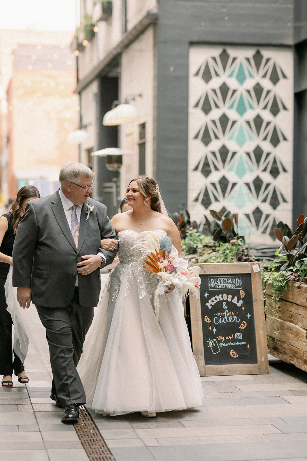 Bride walks down the aisle with her father during her downtown wedding ceremony.
