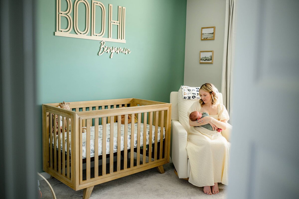 mother snuggling her newborn son while sitting in his nursery