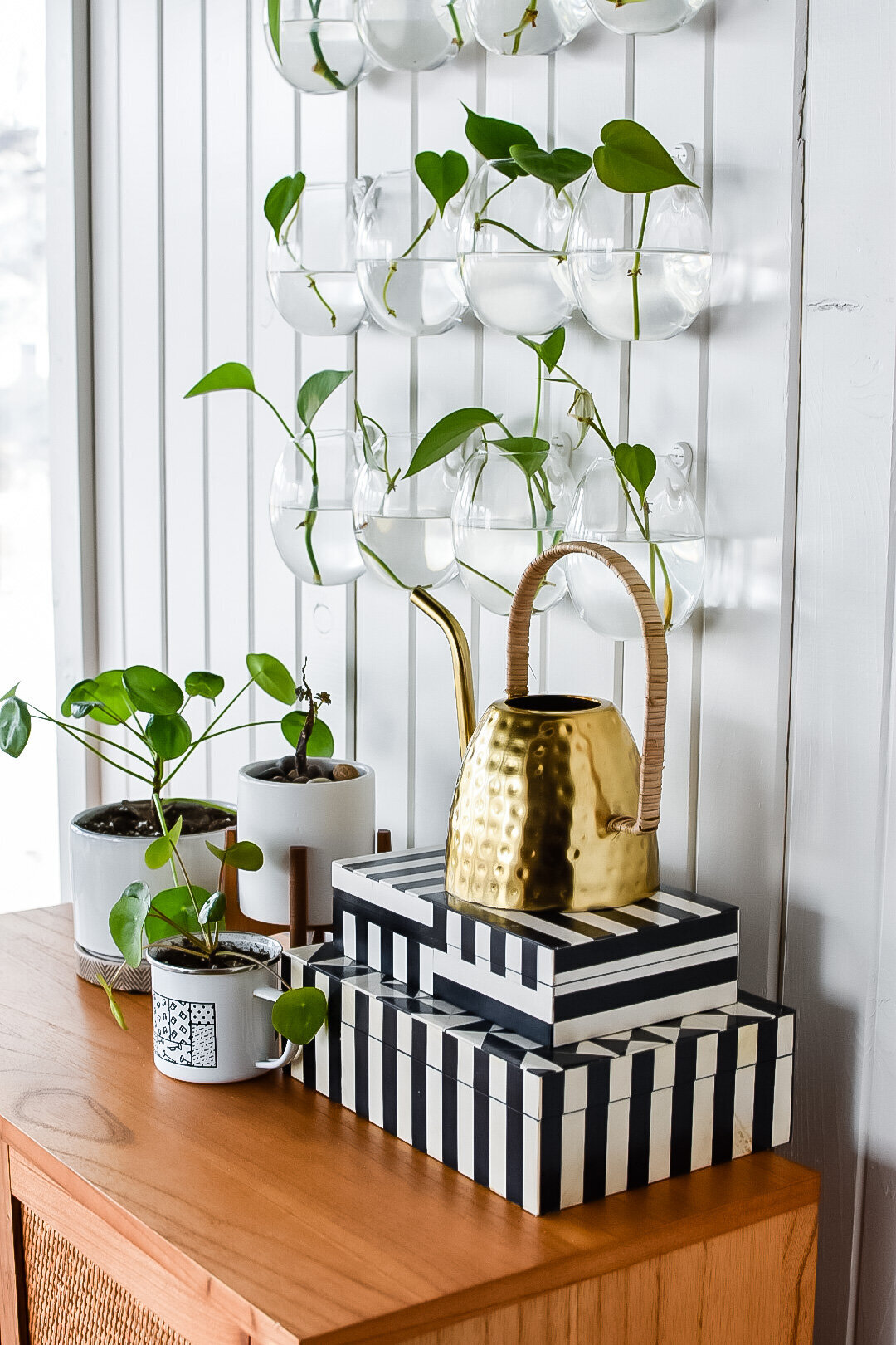 A metal watering can sits on top of two striped decorative boxes