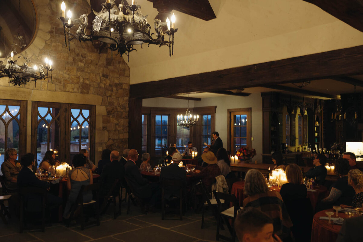 A group of people celebrate at an indoor wedding reception held at the Chateau De Lis in Oregon.
