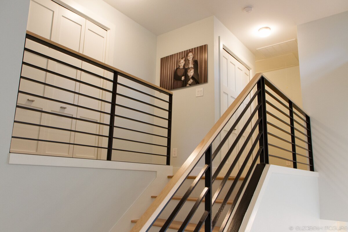 top of stairs in custom home build. iron railings and hard wood floors make this grand stair case shine.