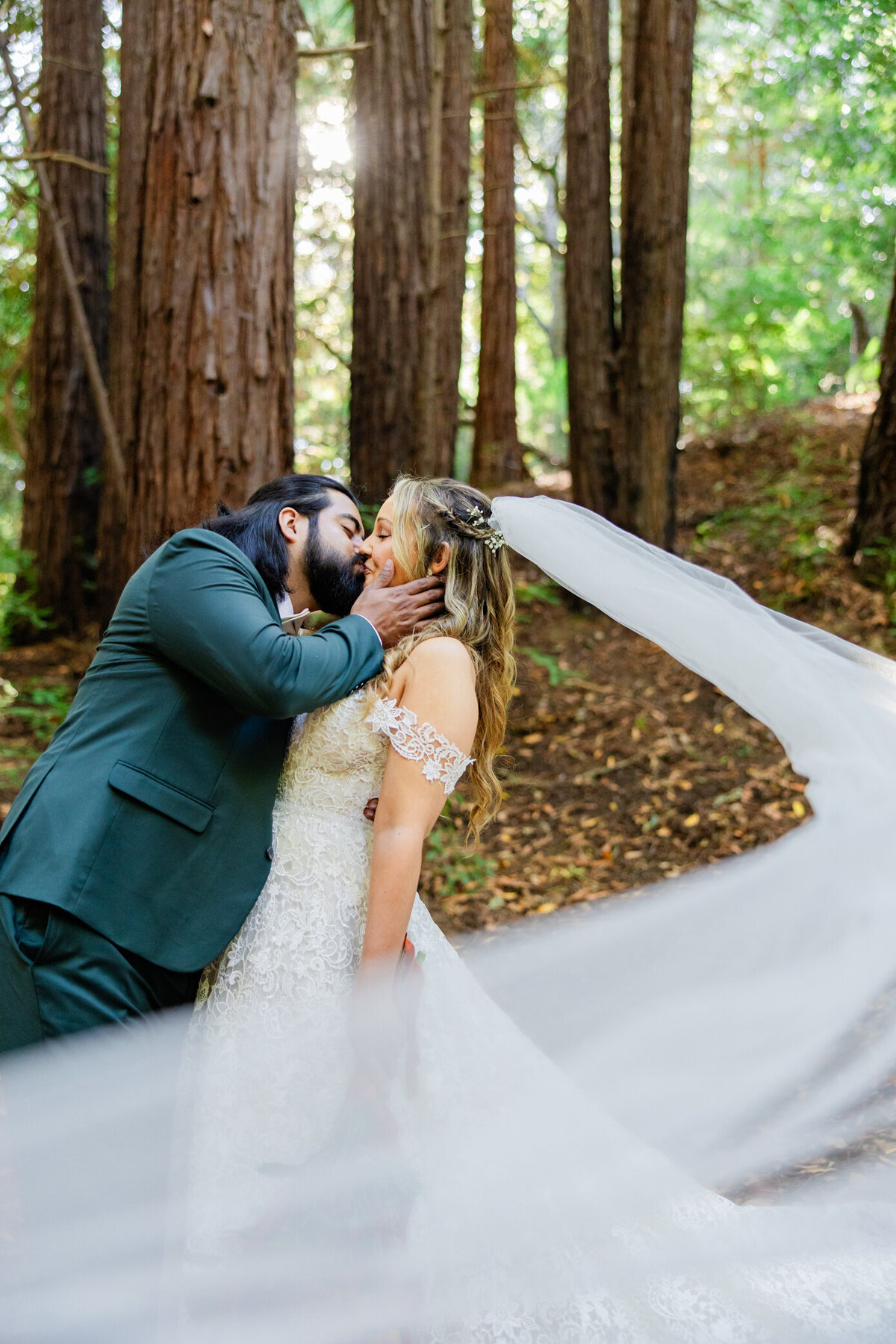bride and groom kiss while the bridal veil flows in the wind