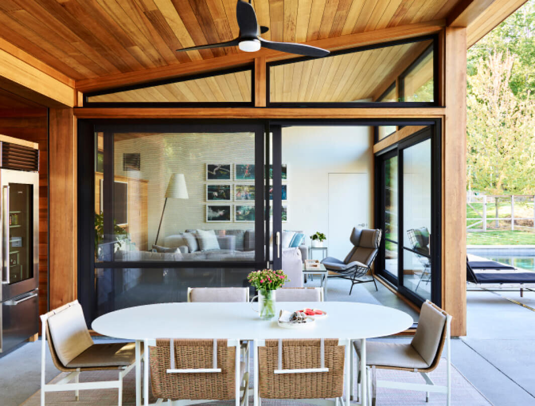 Modern outdoor dining furniture complements the new construction pool house design in Hingham, Massachusetts, blending style and function in an elegant setting.