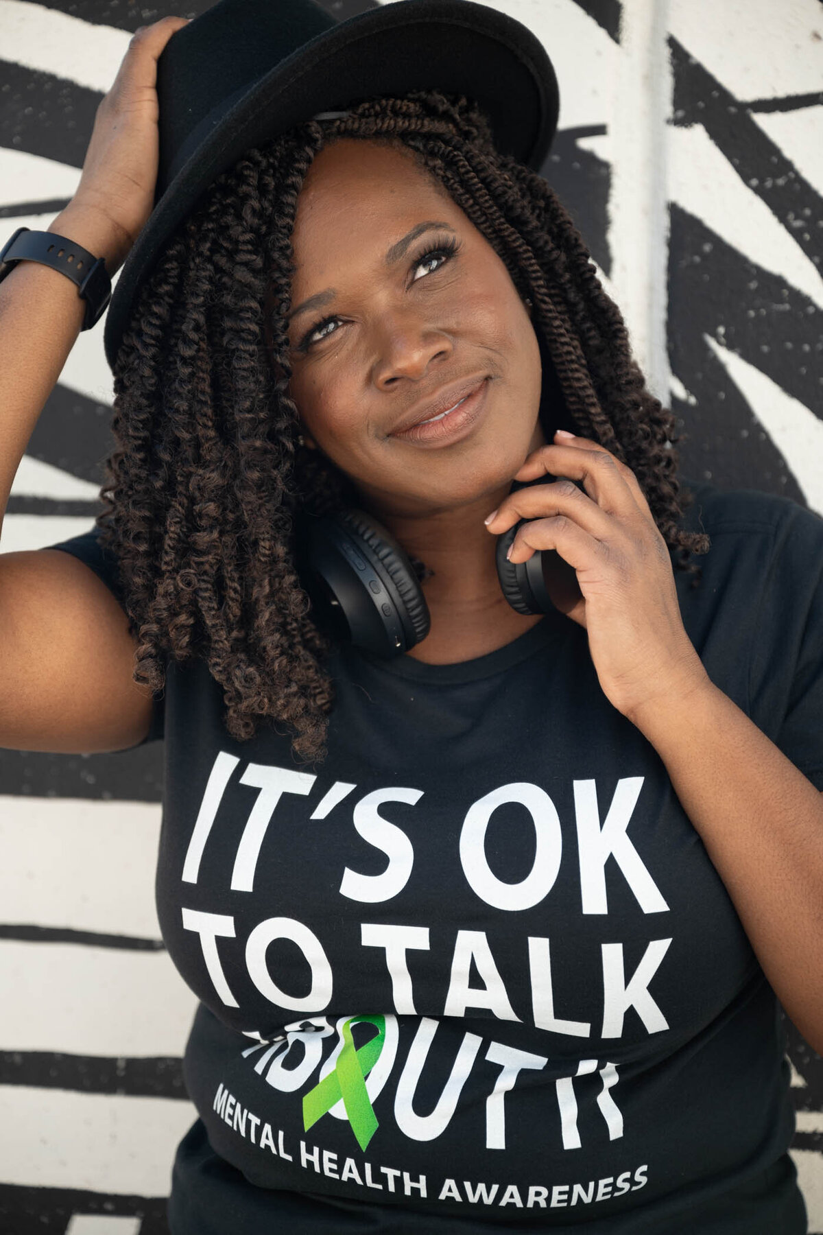 A portrait of a woman on a black and white graffiti wall wearing a t-shirt promoting mental health awareness