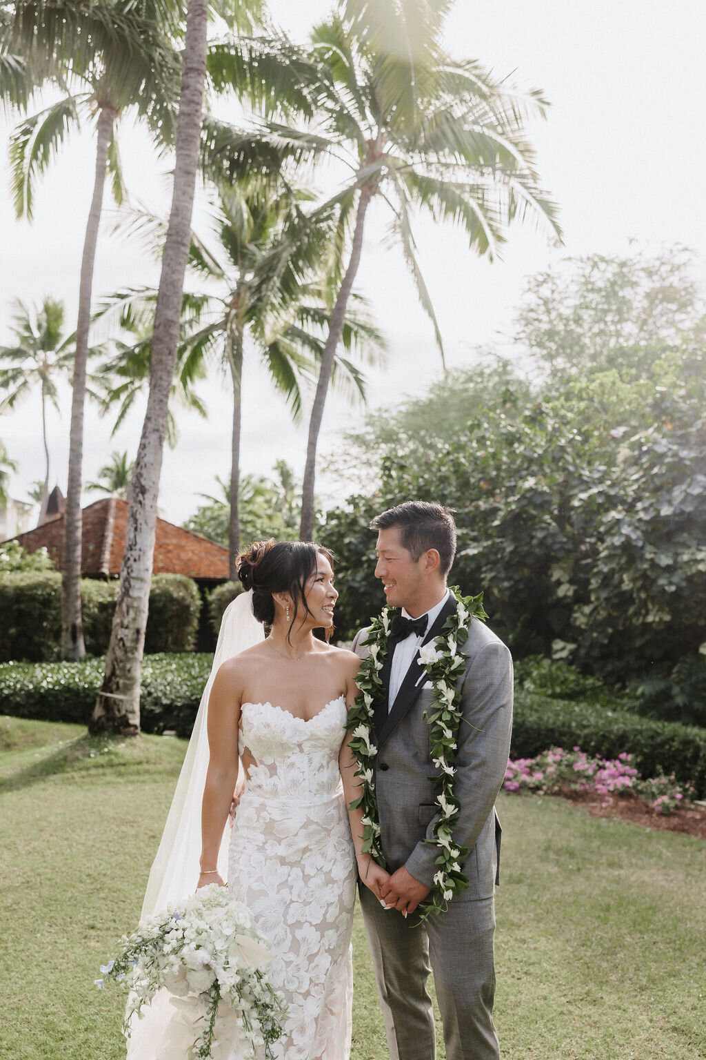 film photo of bride and groom staring lovingly into each others eyes with palm trees behind them in a grassy area at four seasons oahu