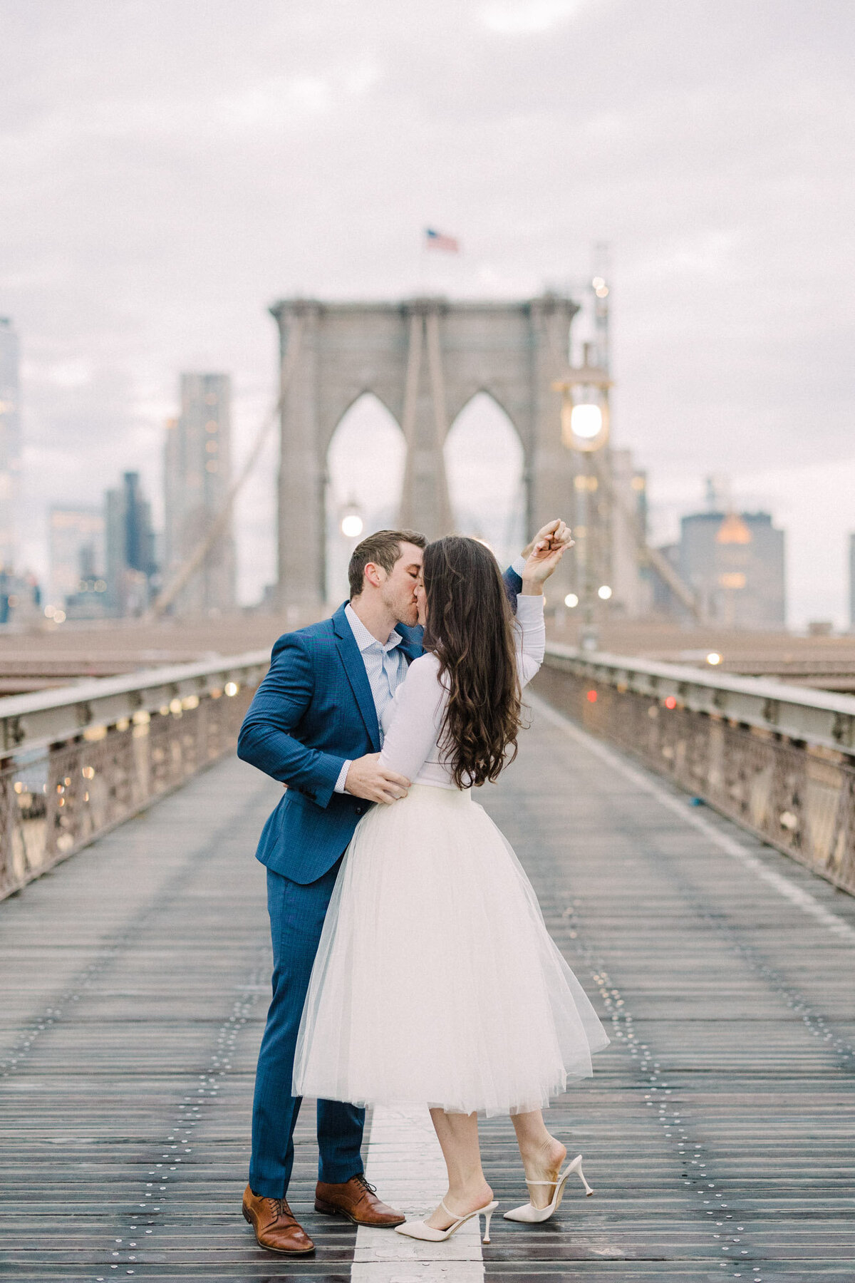 An engagement photo taken at sunrise on the Brooklyn Bridge in New York City