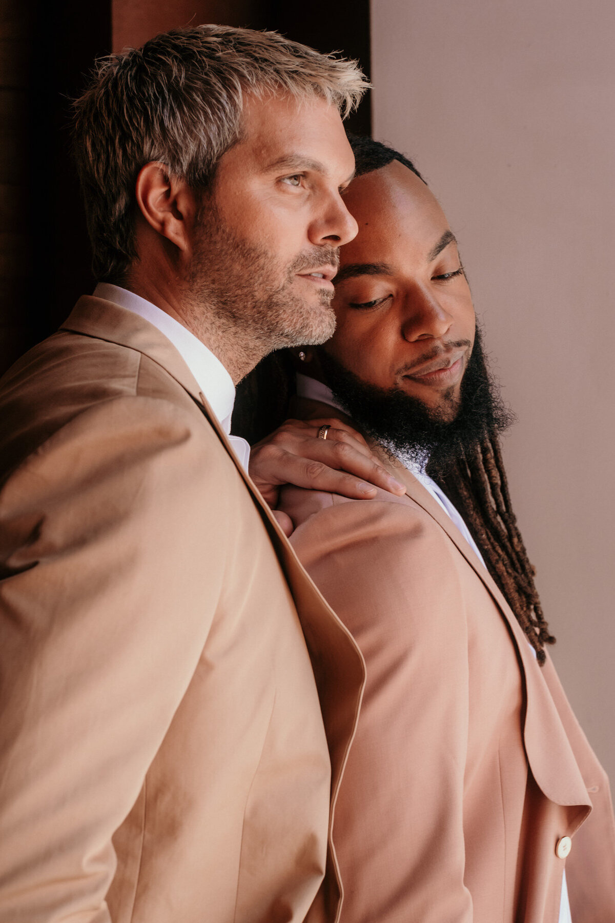 Standing close, one man leans againt his partner, trusting him visibly.