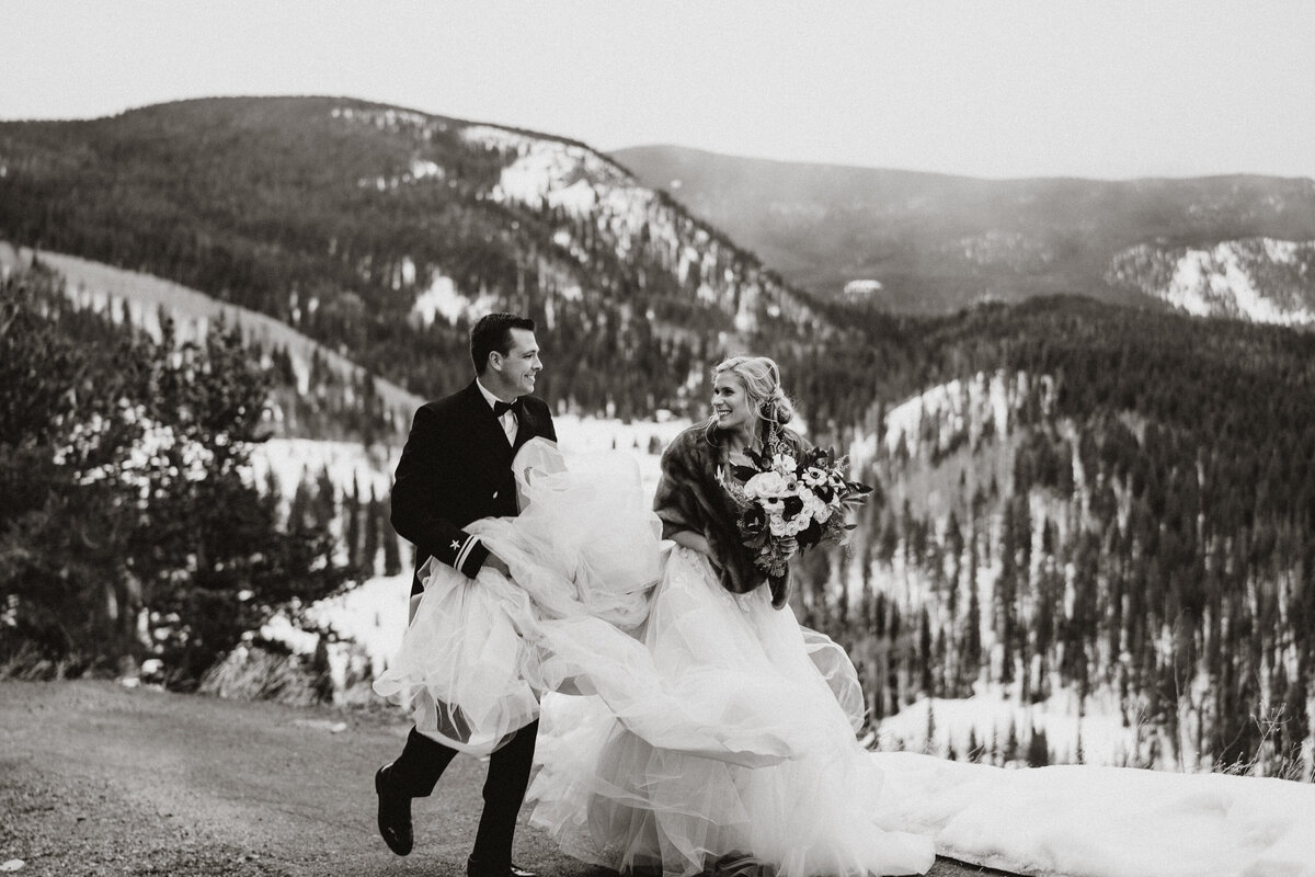 Joyful couple walks through snow after winter wedding in Breckenridge, Colorado mountains.