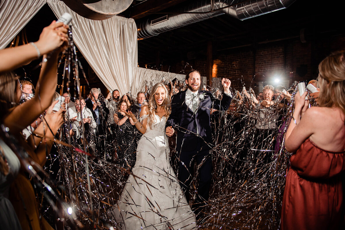 Bride and Groom dancing with guests at reception as they pop silver streamers