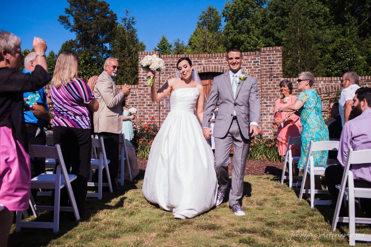 A bride and groom walking back up the aisle in an outdoor ceremony