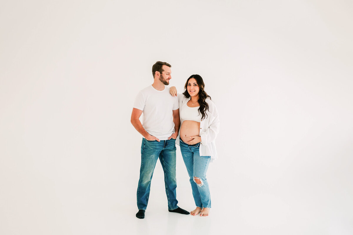 pregnant couple in white tees in maternity photography studio in Springfield MO