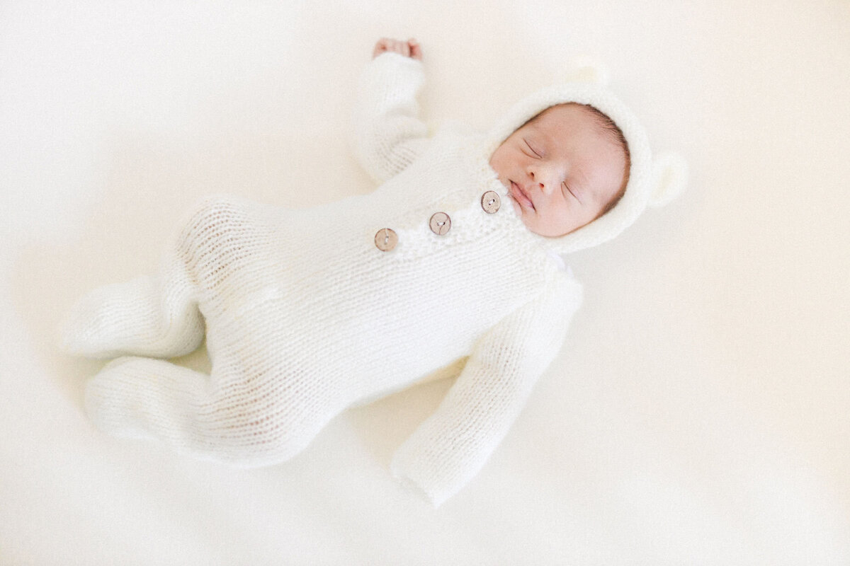 Sleeping newborn baby wrapped in teddy bear outfit in Miami, FL. 