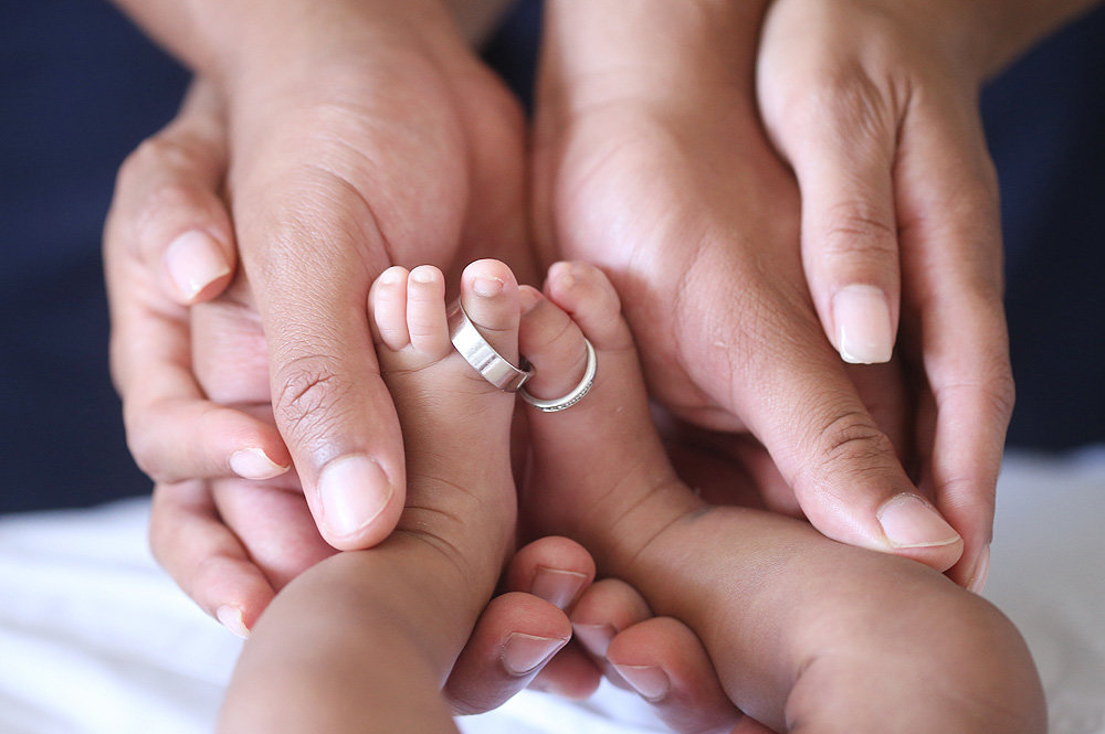 hands holding baby feet with wedding rings