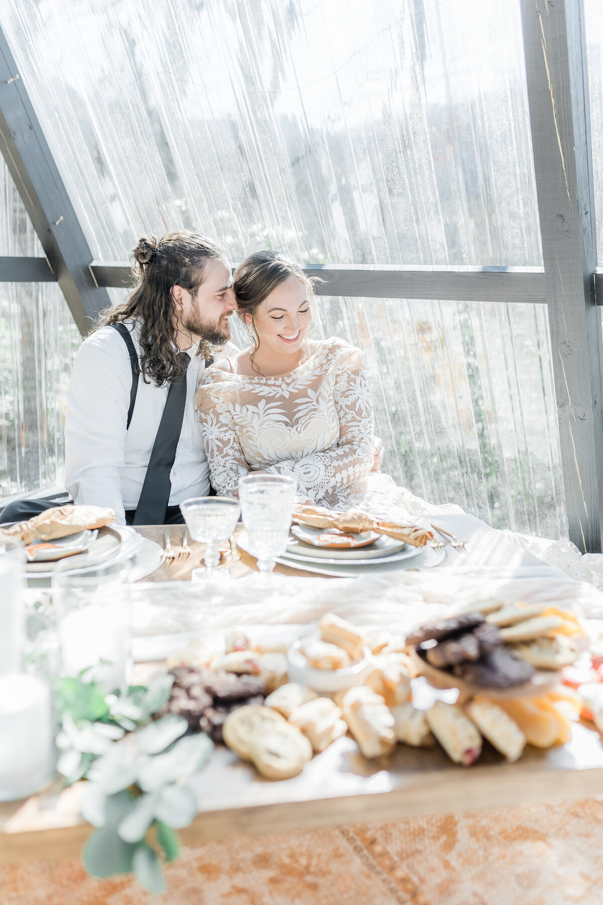 Bride and groom sharing a picnic in their glass cabin,