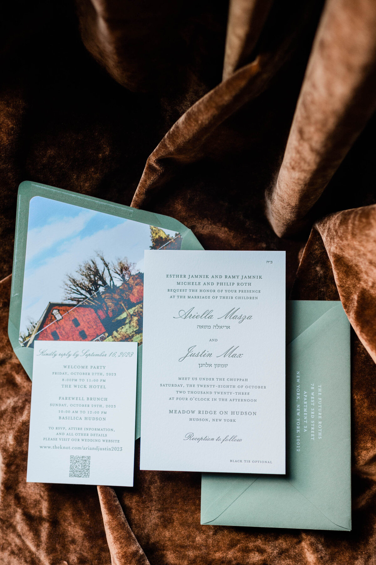 A flat-lay arrangement of the wedding invitation suite, including RSVP details and a photo of a rustic barn