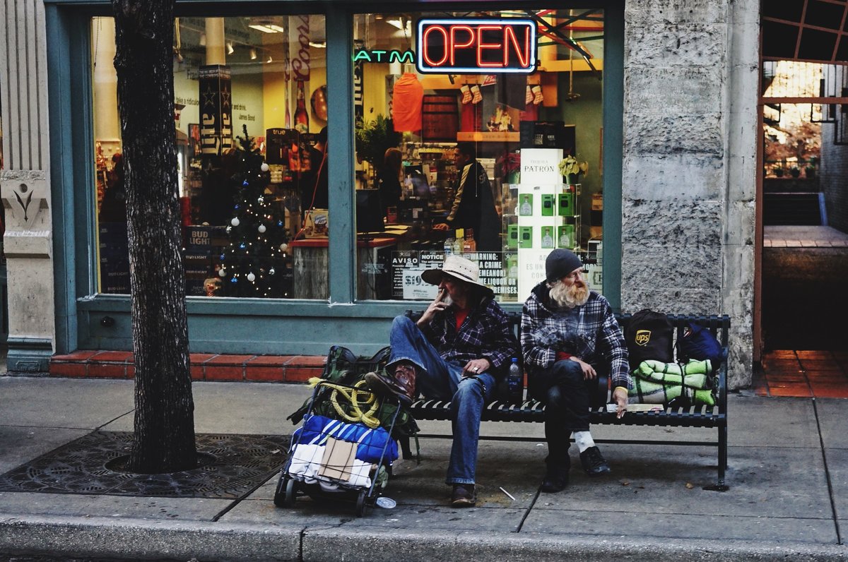 two homeless men smoking on a street bench in San Antonio