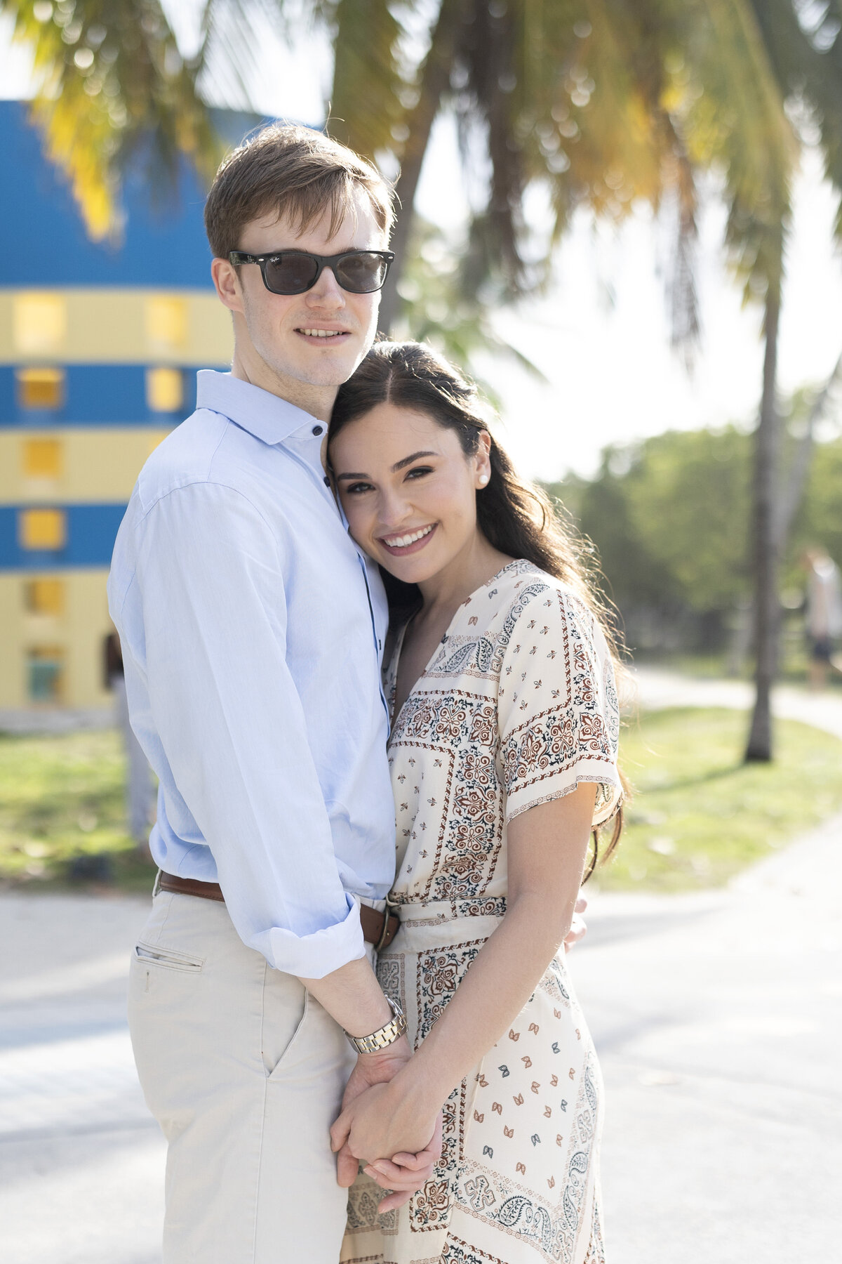 Casual engagement portrait of a couple smiling and holding hands outdoors in Miami, Florida, captured by Rodrigo Varela Photography. Natural and relaxed moment capturing love in a sunny setting.