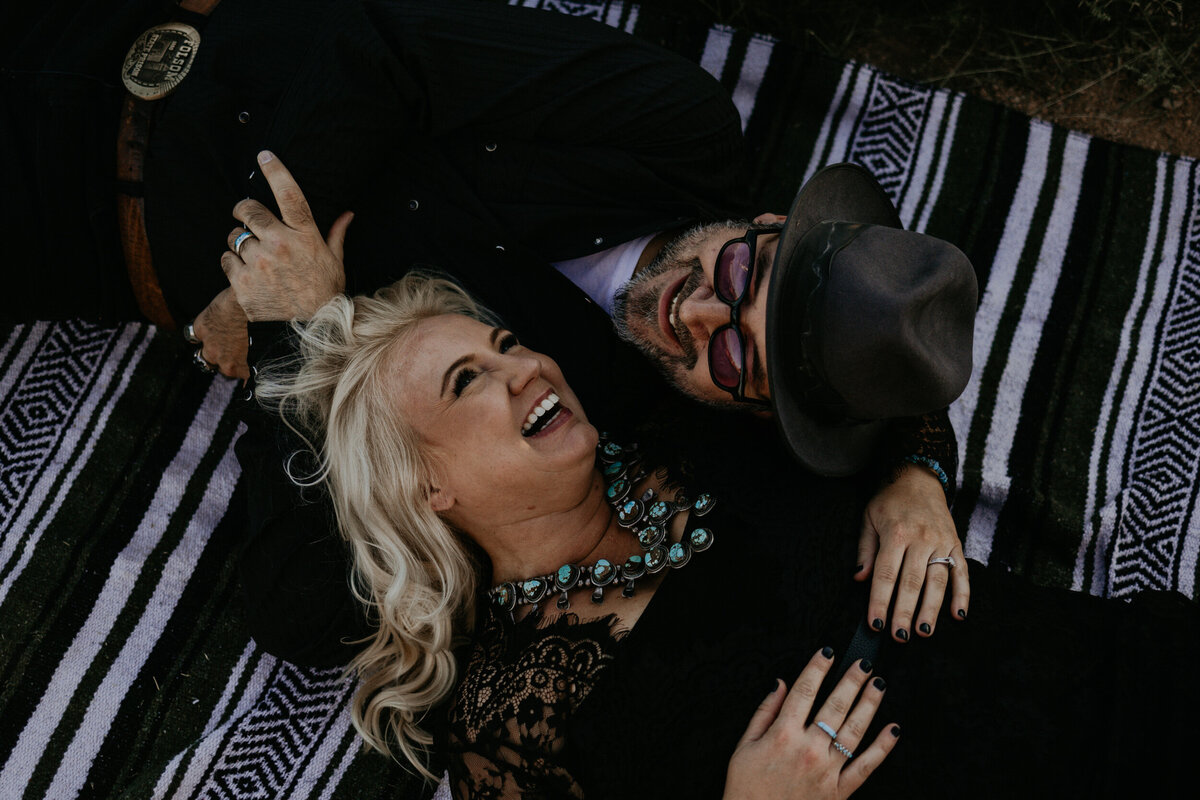engaged couple laying on a blanket together laughing