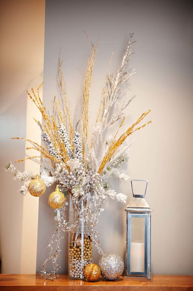 winter wonderland decor with lanterns, gold and silver ornaments, vase with flocked branches and gold sparkle branches