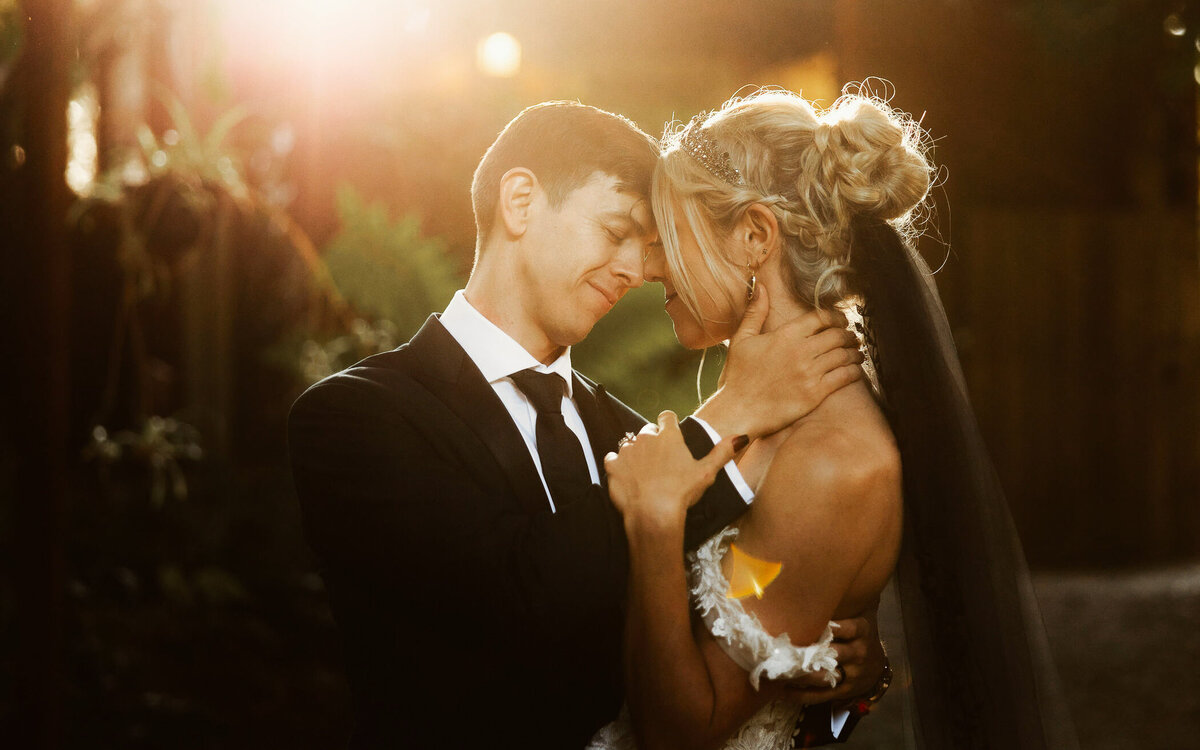 Bride and groom share an intimate embrace in a garden setting, captured in a timeless and cinematic style.