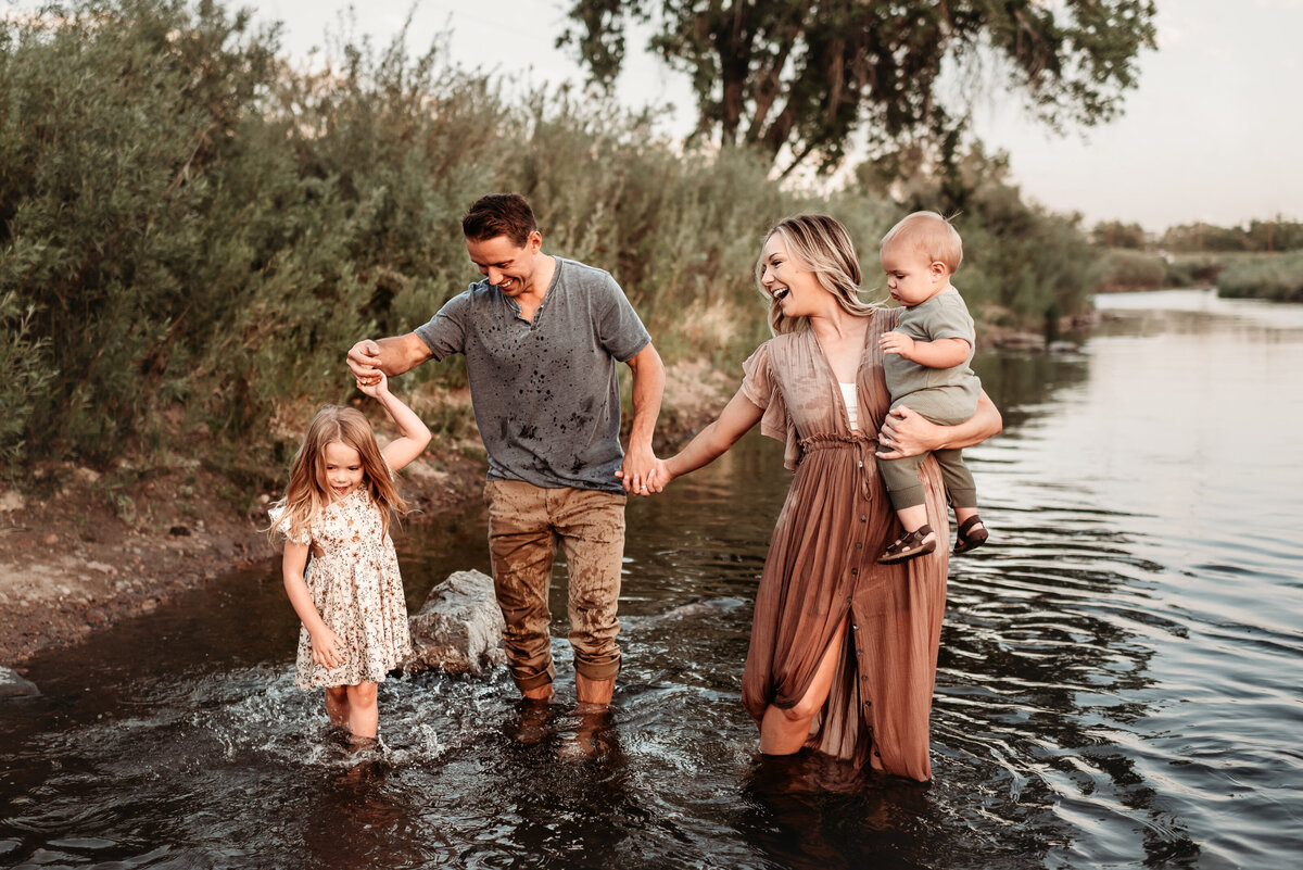 mom dad daughter and son walking through the river in photography clothes having fun