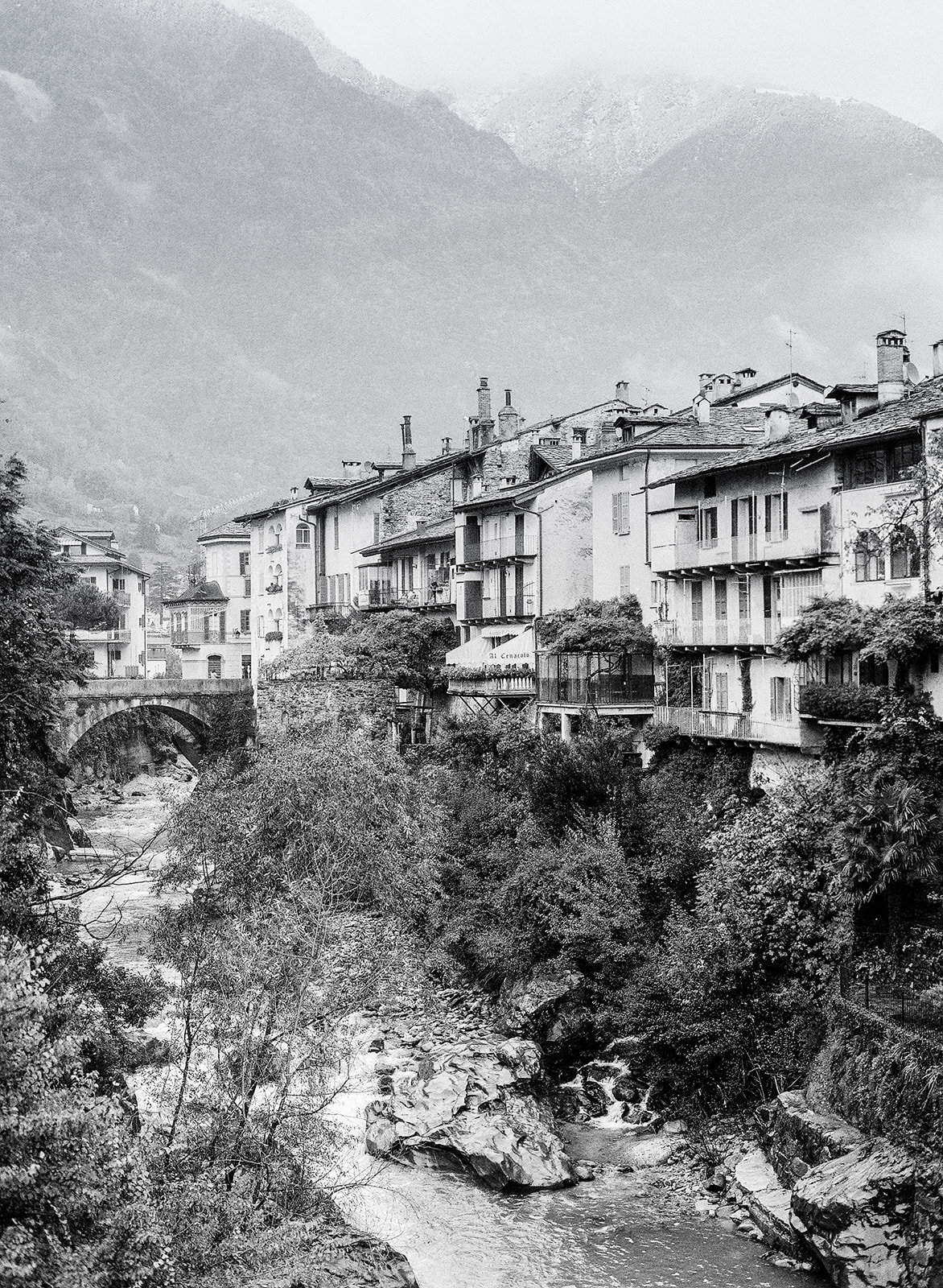 Black and white film photograph of village in the Alps and bride with river flowing