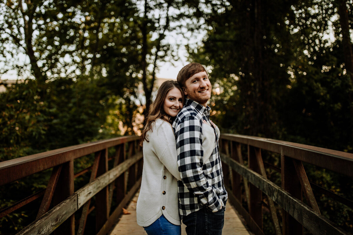 Bride and groom holding hands looking at each other while standing in front of rolling hills with the sunlight coming down on them