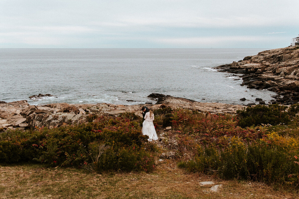 Couple walking towards the water on the cliff, in the backyard of their airbnb venue in Maine.