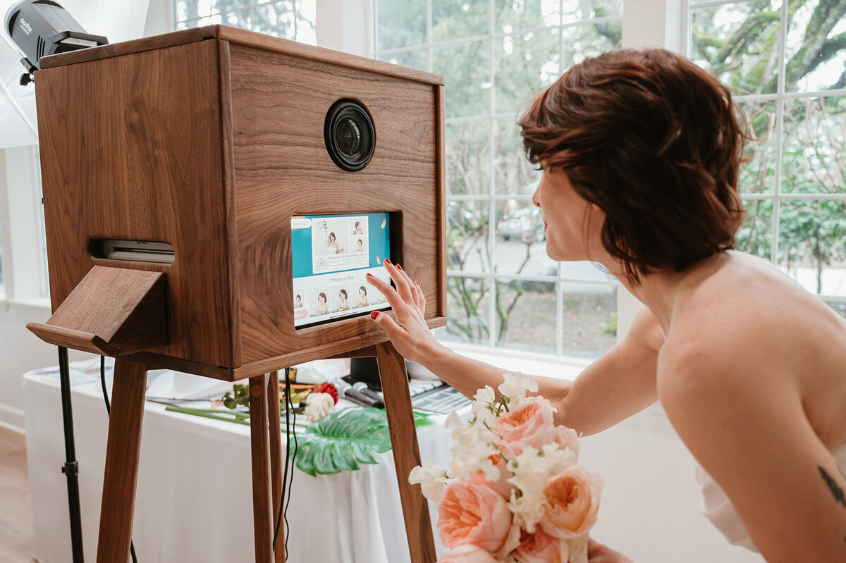 A woman scrolls through the photos displayed on the Birdie Booth, an open air photo booth for weddings.