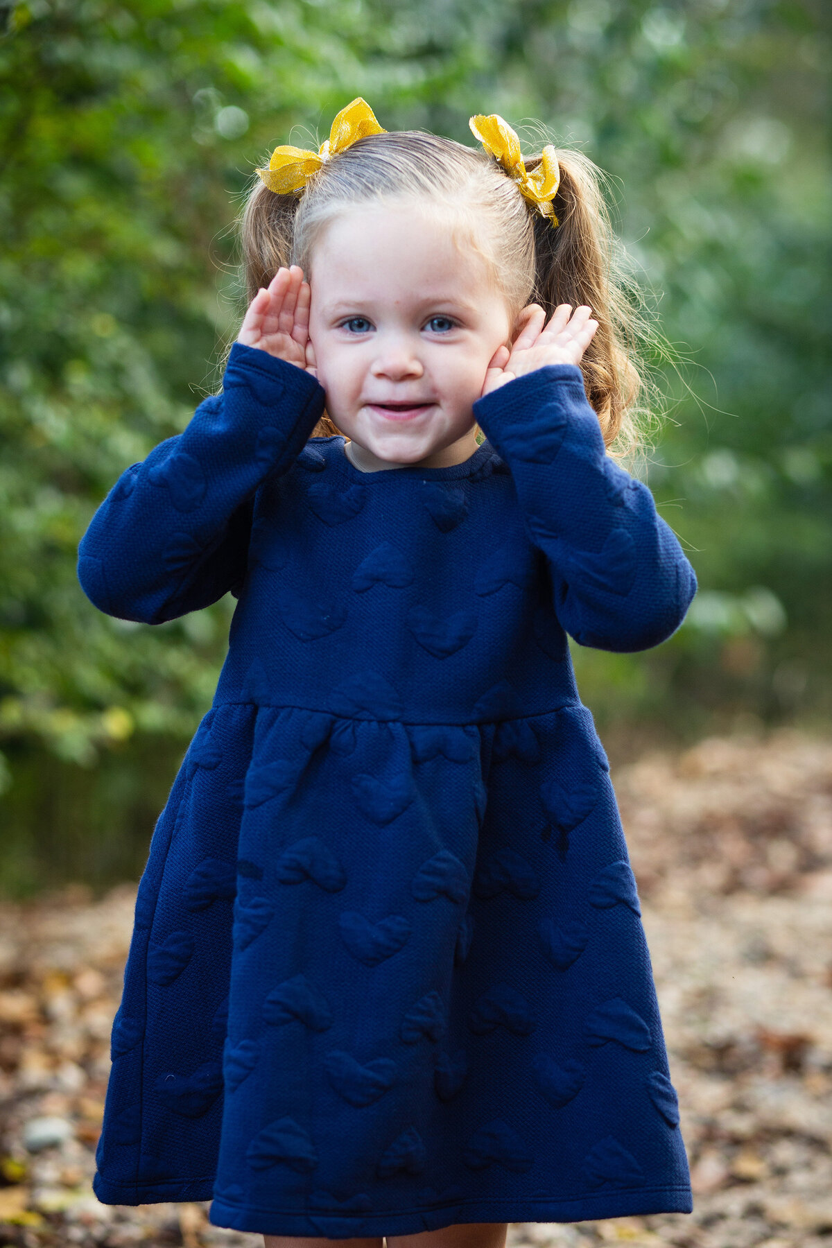 little girl in blue dress playing peek a boo
