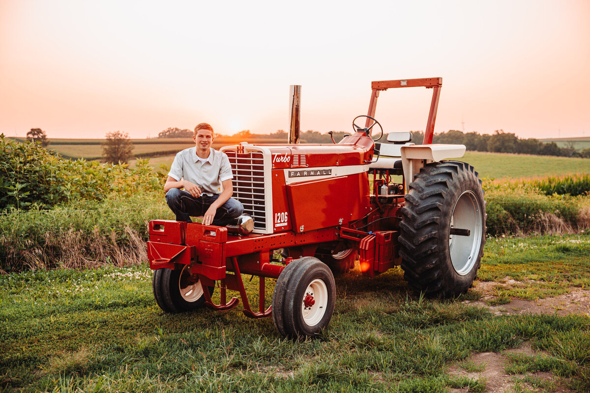 high school guys posing with a tractor on his rural farm in wisconsin