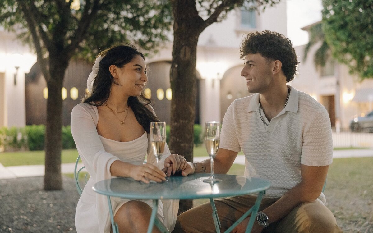 couple shares a glass of champagne during engagement phtoos