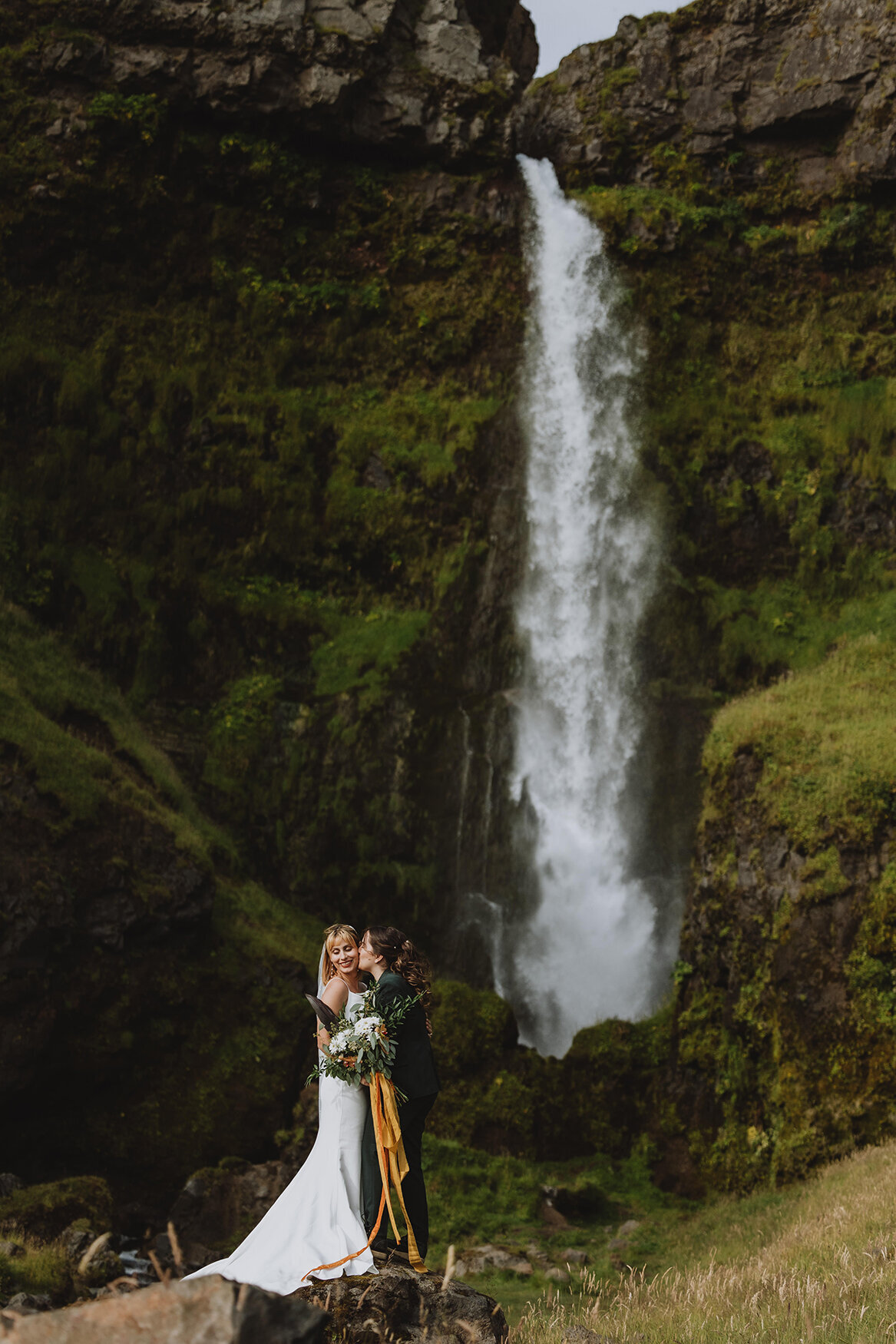 brides in front of waterfall
