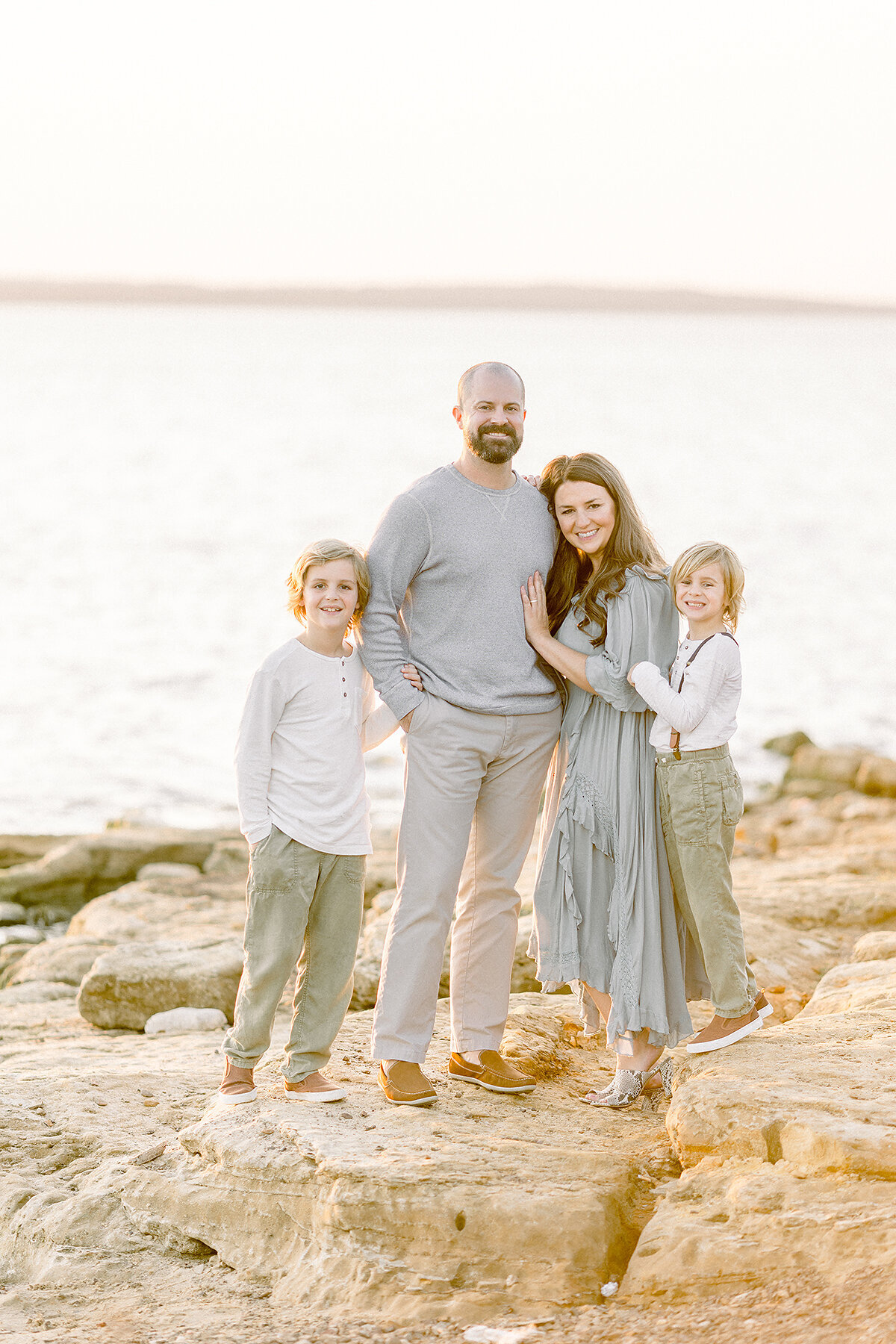 A beautiful Dallas Family posing by a lake on the rocks for family photos.