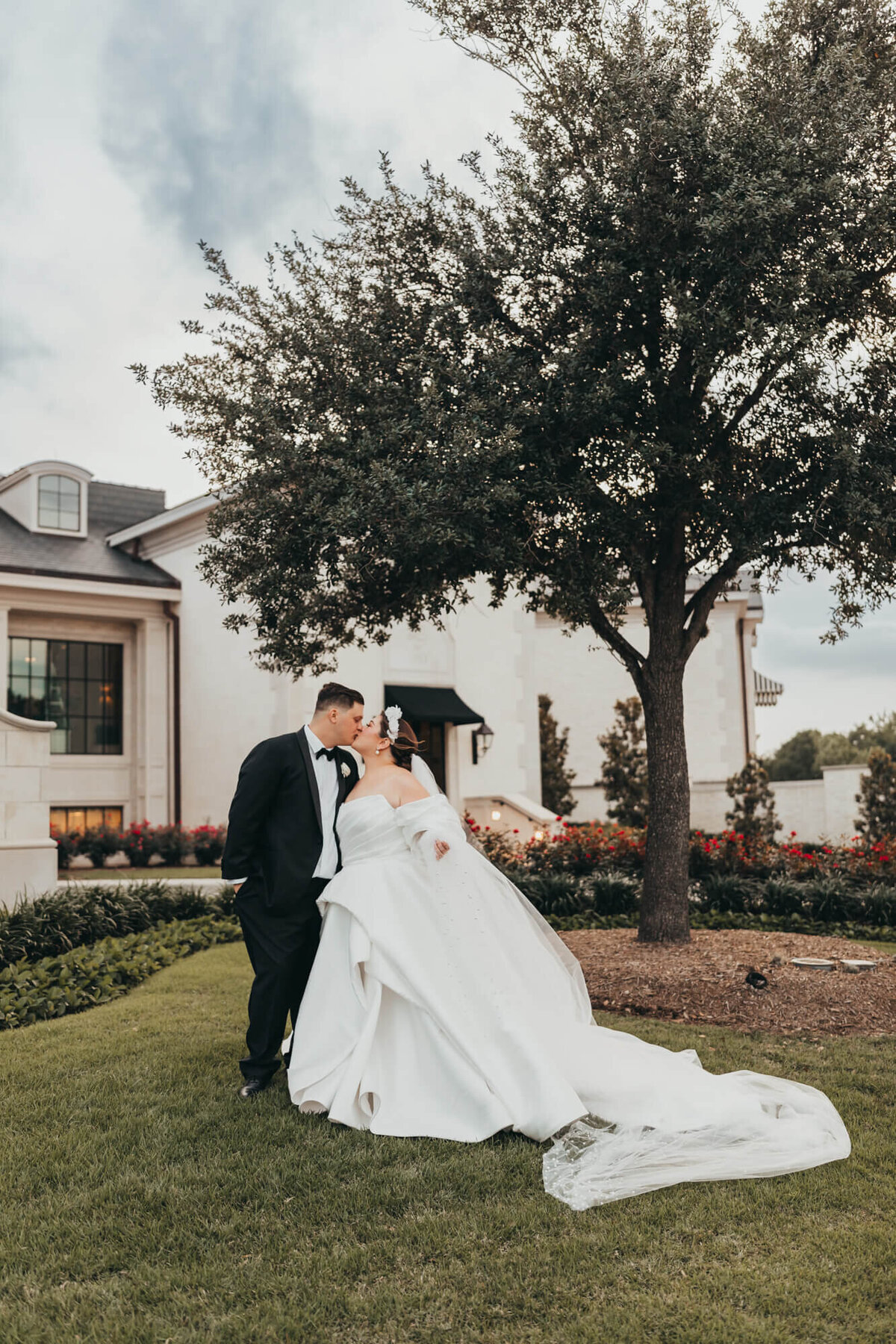 bride and groom kiss in front of their reception venue, Lakeside Country Club in Houston Texas.